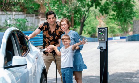 Téléchargez les photos : Vacances route familiale avec véhicule électrique, belle voiture familiale recharge EV avec de l'énergie verte et propre. Voyage en voiture naturel et écologique pour un environnement durable. Perpétuel - en image libre de droit