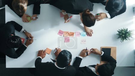 Von oben nach unten ariel Blick auf professionelle Business-Team verwenden bunte Haftnotizen Brainstorming-Idee im Besprechungsraum. Diverse Gruppen teilen sich Finanzplan oder Projekt und zeigen auf Whiteboard. Direktion.