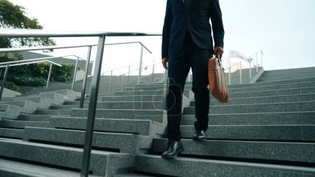 Photo for Closeup of skilled manager walking down stair with a bag and return to home. Closeup of project manager leg getting fired and walk to dormitory. Investor with untidy suit. Focus on leg. Exultant. - Royalty Free Image