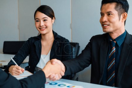 Photo for Business people agreement concept. Asian Businessman do handshake with another businessman in the office meeting room. Young Asian secretary lady sits beside him. uds - Royalty Free Image