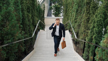 Photo for Caucasian businessman walking up stair and calling manager by using smart phone. Top view of manager talking marketing team and planning financial strategy by telephone while going up stair. Urbane. - Royalty Free Image