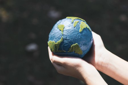 Photo for Young boys hand holding planet Earth globe at natural park background as Earth day to save this planet with ESG principle and environment friendly energy for brighter future. Gyre - Royalty Free Image