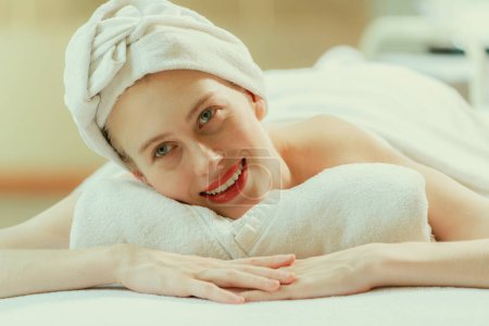 Photo for A beautiful young woman lies on a spa bed, her body relaxed and at peace. Pretty caucasian girl surrounded by the spa environment and the gentle aroma of essential oils. Close up. Tranquility. - Royalty Free Image