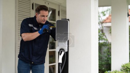 Photo for Qualified technician install home EV charging station, providing maintenance service for electric vehicles battery charging platform at home. EV car technology for residential utilization. Synchronos - Royalty Free Image