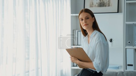 Photo for Friendly psychologist woman in clinic office professional portrait with smile and holding clipboard for patient to visit psychologist. The experienced and prim confident psychologist - Royalty Free Image