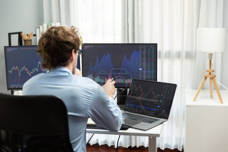 Photo for Young investor in stock trader pointing on dynamic exchange rate on laptop and pc screen in dynamic market graph online in real time at modern home office, analyzing financial technology data. Gusher. - Royalty Free Image