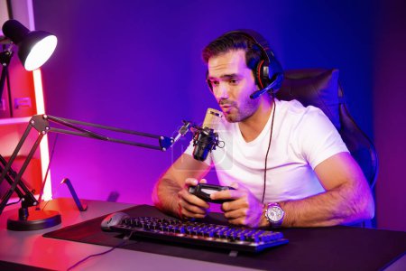 Photo for Smart gaming streamer talking with team member players with joystick to control game, mic for communicate with others on streaming live on social media at digital neon lighting studio room. Surmise. - Royalty Free Image