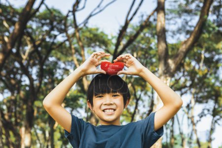 Umweltbewusstseinskampagne zur Förderung des Umweltschutzes mit glücklichen asiatischen Jungen mit Herz als Symbol der Liebe zur Natur und der Ökologie für eine zukünftige grünere nachhaltige Erde. Kreisel