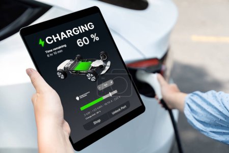 Branchez le chargeur EV main dans le véhicule électrique pour recharger la voiture EV, affichage de l'état de la batterie sur l'application de la tablette EV. Énergie propre et durable future pour les transports. Perpétuel