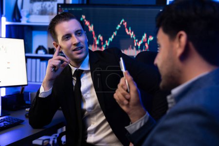 Téléchargez les photos : Deux traders boursiers discutent sur le graphique d'investissement dynamique, tendance de profit élevé en actions de devises. Affichage de données sur les avantages financiers à l'écran du moniteur au néon sur le lieu de travail. Vendu. - en image libre de droit