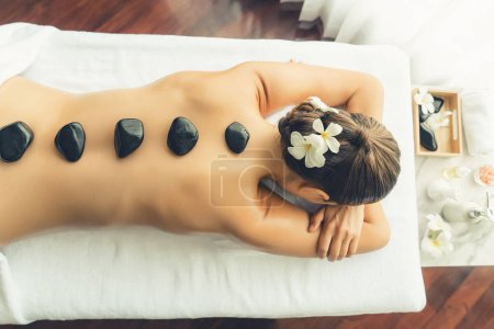 Photo for Panorama top view hot stone massage at spa salon in luxury resort with day light serenity ambient, blissful woman customer enjoying spa basalt stone massage glide over body. Quiescent - Royalty Free Image