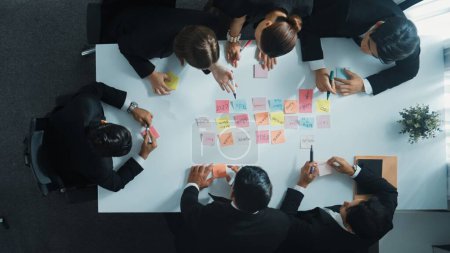 Photo for Top down ariel view of professional business team use colorful sticky notes brainstorming idea at meeting room. Diverse group share financial plan or project and point at whiteboard. Directorate. - Royalty Free Image