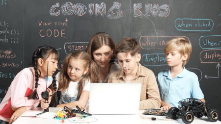 Photo for Diverse student writing engineering code while boy fixing mother board. Teacher giving advice and teaching about robotic system while learner studying and learning about coding prompt. Erudition. - Royalty Free Image