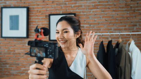 Photo for Woman influencer shoot live streaming vlog video review clothes social media or blog. Happy young girl with apparel vivancy studio lighting for marketing recording session broadcasting online. - Royalty Free Image