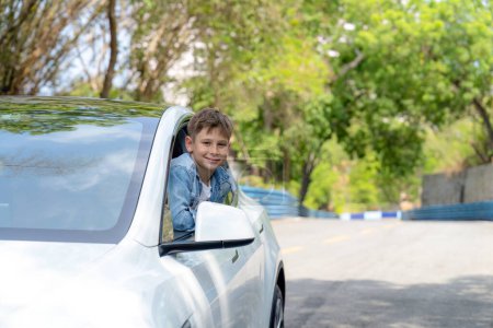 Emocionado y feliz niño pequeño con sonrisa en su cara aparecen en la ventana del coche mientras conduce, expresión lúdica y alegre, mientras que en el viaje por carretera que viaja en coche durante el verano. Perpetuo
