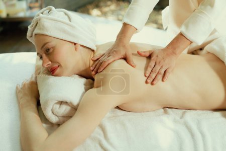 Foto de Hermosa mujer joven se encuentra en la cama de spa durante el masaje de espalda. Atractiva mujer caucásica que tiene masaje de espalda en el salón de spa tradicional, sala de spa. Relajante y concepto saludable Tranquilidad. - Imagen libre de derechos