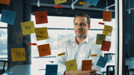 Photo for Portrait of professional businessman analysis marketing idea on sticky notes. Smiling caucasian manager thinking and decide about marketing campaign from creative business ideas. Manipulator. - Royalty Free Image