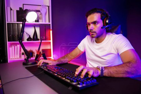 Photo for Serious face gaming streamer concentrating gaming players trying to pass at mission completed, using headset and mic for communicate others on streaming live at neon lighting studio room. Surmise. - Royalty Free Image