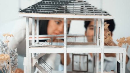 Photo for Close up of cooperative professional engineer working together to measuring house model structure. Young beautiful architect measure house model while male engineer support performance. Immaculate. - Royalty Free Image