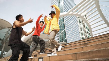 Happy hipster group walking up stair while perform street dance. Attractive asian dancer dancing together with multicultural friend at city. Free style, life style. Outdoor sport 2024. Sprightly.