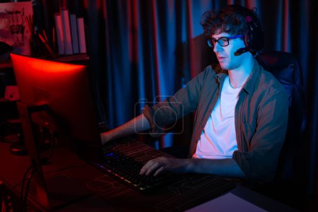 Lächelnde junge Gaming-Streamer-Team spielt mit Steuerknüppel auf Esport online auf PC-Kampfspiel, versuchen Sie, Konkurrenten bei der Strategieplanung für die nächste härtere an roten Neonbeleuchtung modernen Raum zu gewinnen. Gusher.