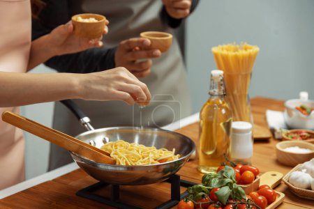 Photo for Close up of hand couple chef influencers cooking spaghetti mix ingredient taking to frying pan, putting seasoning and tasty sauce to make good flavor, Concept of presenting homemade food. Postulate. - Royalty Free Image