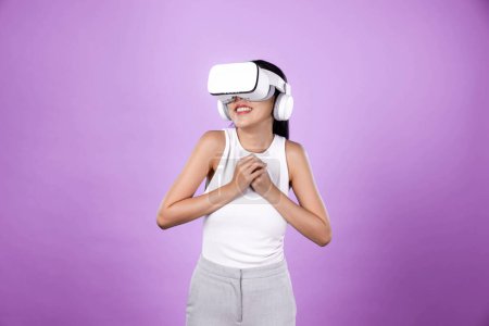 Téléchargez les photos : Femme intelligente debout avec fond rose portant casque VR connectant métaverse, technologie futuriste de la communauté du cyberespace. Femme élégante excitée de voir généré des paysages virtuels. Hallucination. - en image libre de droit