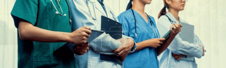 Photo for Confident and professional team of medical staff stand in line together as healthcare service and doctor leadership at hospital background. Teamwork lead to successful medical treatment.Panorama Rigid - Royalty Free Image