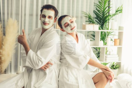 Photo for Blissful couple in bathrobe with facial cream mask enjoying serene ambiance of spa salon resort or hotel during holiday. Pampering face spa and skincare treatment with essence relaxation. Quiescent - Royalty Free Image