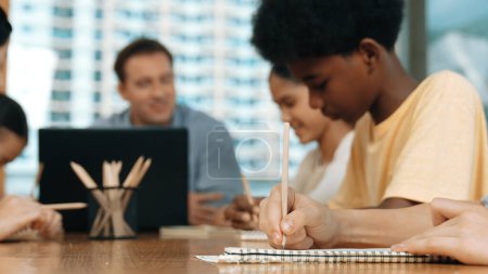 Photo for Closeup of student hand taking a note while girl ask teacher a question. Diverse student learning and study with smart happy instructor in classroom. Focus on hand. Creative education. Edification. - Royalty Free Image