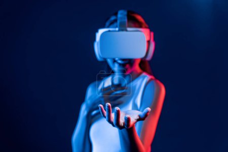 Foto de Smart Female de pie rodeada de auriculares VR de neón que conectan tecnología de comunidad ciberespacial metaversa y futurista. Mujer elegante uso de la celebración de la mano generado objeto virtual. Alucinaciones. - Imagen libre de derechos