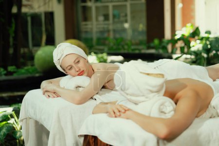 Photo for A portrait of a couple of a beautiful young caucasian woman with white towel rest on comfortable spa bed with relaxation while having body massage with professional masseur at spa salon.Tranquility. - Royalty Free Image