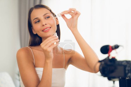 Photo for Young woman making beauty and cosmetic tutorial video content for social media. Beauty blogger smiles to camera while showing how to beauty care to audience or followers. Unveiling - Royalty Free Image