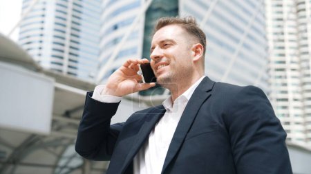 Photo for Smart caucasian businessman calling his colleague to plan financial strategy while standing at urban city. Project manager using his mobile phone to communicate with marketing team. Lifestyle. Urbane. - Royalty Free Image