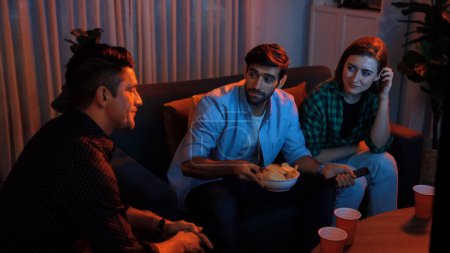 Photo for Top view of caucasian father and relaxed mother watching movie while eating snack with friend. Happy family with colleague looking at television while dad hold snack bowl at living room. Convocation. - Royalty Free Image