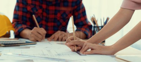 Photo for Cropped image of cooperative architect team decide and work together on meeting table with house model, safety helmet and architectural plan scatter around. Closeup. Focus on hand. Burgeoning. - Royalty Free Image