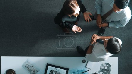 Photo for Top down view of smart engineer talking about turbine engine design while standing at meeting table with gear. Aerial view of technician discussing about electronic generator structure. Alimentation. - Royalty Free Image