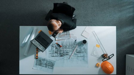 Photo for Architect engineer working while working on laptop with sticky notes and calculator to design building construction. Smart manager working and using calculator to calculate blueprint. Alimentation. - Royalty Free Image