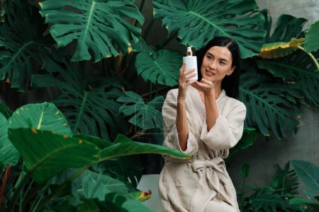 Photo for Tropical and exotic spa garden with bathtub in modern hotel or resort with woman in bathrobe holding beauty skincare product while enjoying leisure lush with greenery foliage background. Blithe - Royalty Free Image