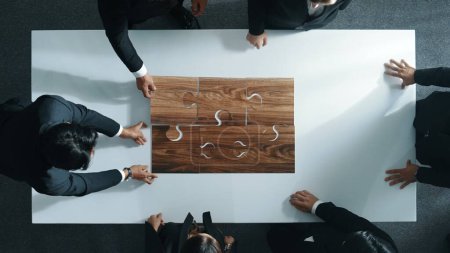 Photo for Top view of business people putting jigsaw together at meeting room. Professional marketing team standing at table while gathering puzzle piece. Show unity, cooperation and team working. Directorate. - Royalty Free Image