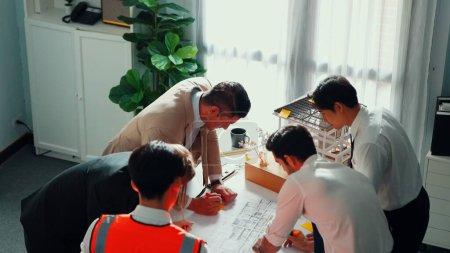 Photo for Top view of professional architect engineer team inspect house model while manager holding blueprint and asking about building construction. Group of diverse engineer working together. Alimentation. - Royalty Free Image