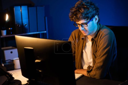 Photo for Young businessman concentrating on pc for creative startup project job at neon light modern office. Thinking marketing network online planning of creator to market channel design concept. Gusher. - Royalty Free Image