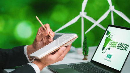 Geschäftsmann, der im Büro arbeitet und einen Plan oder ein Projekt über umweltfreundliche alternative Energien mit Solarzellentechnologie entwickelt, zeigt auf einem Computerbildschirm für eine grünere Umwelt als Teil der CSR-Bemühungen. Kreisel
