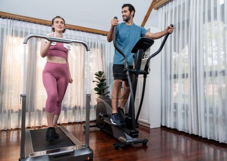 Athletic and sporty young couple or fitness buddy running on running machine together, home body workout exercise session as healthy sport lifestyle at home. Gaiety home exercise workout training.