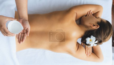 Téléchargez les photos : Panorama vue de dessus masseur mains verser de l'huile d'arôme sur la femme dos. Masseuse préparer la procédure de massage à l'huile pour le client au salon de spa dans un complexe de luxe. Huile d'arôme massage du corps concept de thérapie. Tranquillité - en image libre de droit