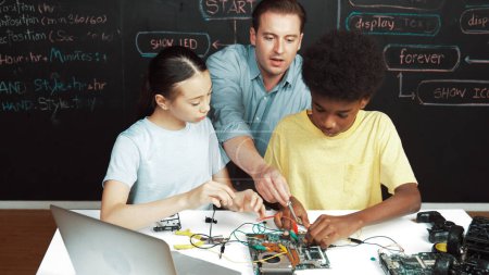 Smart Mentor lehren Hauptplatinenkonstruktion, während diverse Teenager Lernsystem. Der Lehrer erklärt die Struktur des Motherboards, während der Schüler lernt, elektronische Geräte zu benutzen. Erbauung.