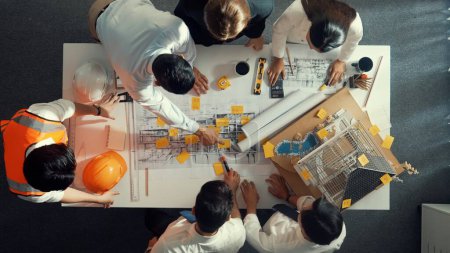 Photo for Top down view of skilled engineer team talking while looking at project plan. Aerial view of group of smart interior designer working together and planning for engineering construction. Alimentation. - Royalty Free Image