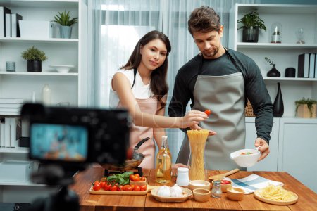 Photo for Couple chef influencers on cooking show presenting ingredient of spaghetti, meat, chilli, tomato, garlic and seasoning sauces homemade special recipe recording on camera on live channel. Postulate. - Royalty Free Image