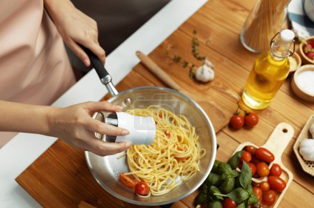 Photo for Close up of hand chef influencer cooking spaghetti mix ingredient taking to frying pan, putting seasoning and tasty sauce to make good flavor, Concept of presenting homemade food at studio. Postulate. - Royalty Free Image