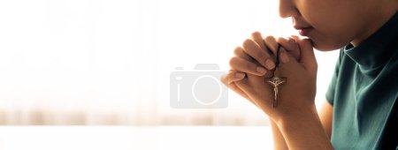Photo for Praying female hand holding cross while praying to god faithfully. Concept of hope, religion, faith, christianity and god blessing for happiness. Bright light, white blurring background. Burgeoning. - Royalty Free Image